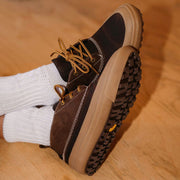 Women's Carson 3 Eye Boot in Bourbon leather, outsole view worn with white socks on a wood floor