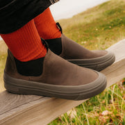 Person sitting on a wooden fence wearing Ballard Boots in Charcoal with red socks.
