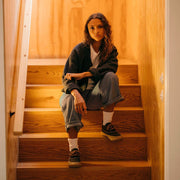 Women's Carson 3 Eye Boot in Bourbon leather, worn by a person seated on wooden stairs