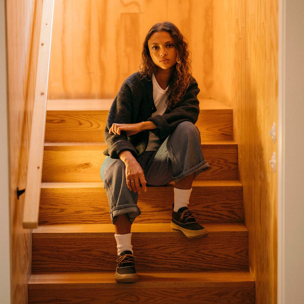 Women's Carson 3 Eye Boot in Bourbon leather, worn by a person seated on wooden stairs