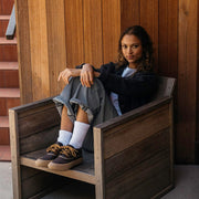 Women's Carson 3 Eye Boot in Bourbon leather, worn by a person seated in a wooden chair with white socks