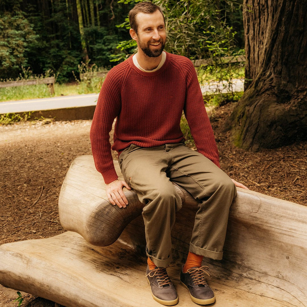 Men's Hermosa Sneaker in Charcoal leather, worn with olive pants by a person seated on a log