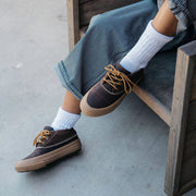Women's Carson 3 Eye Boot in Bourbon leather, worn with white socks, feet resting on a wooden chair