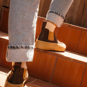Women's Ballard Boot in Coffee Bean leather, worn with rolled jeans, stepping on a terracotta ledge