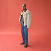 Men's Larkspur Lug Boat Shoe in Dark Chocolate leather, worn by a person standing on a coral background in a light jacket