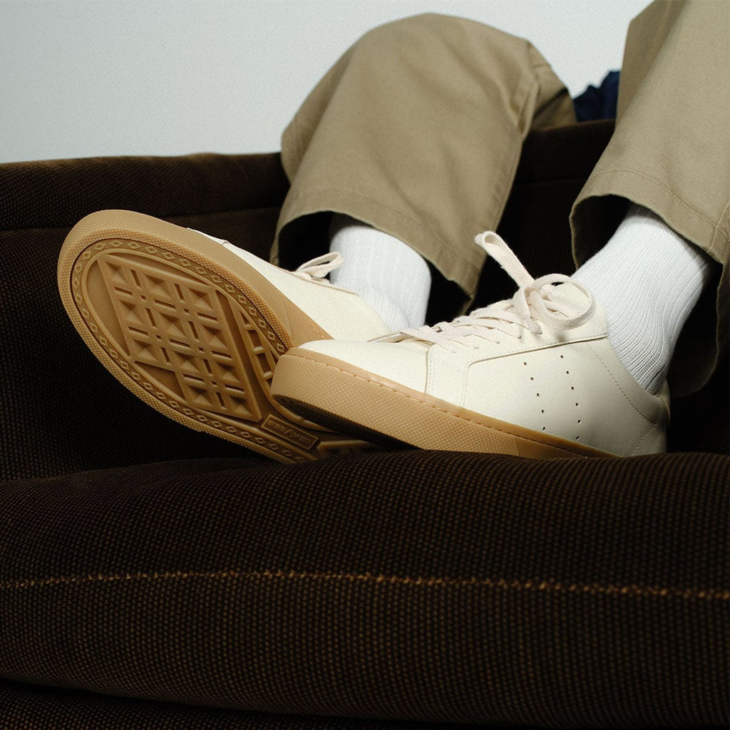 Men's Diamond Cup sneaker in Black leather, ecru pair worn with khaki pants, sole raised on a brown sofa