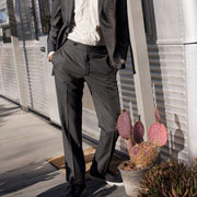 Men's Hermosa Sneaker in Black canvas, worn with gray suit pants on a porch