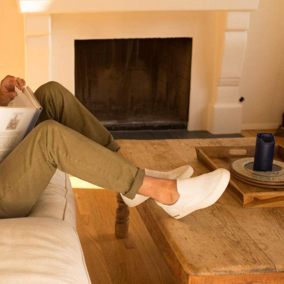 Men's Hawthorne Slip On in Bleach fabric, worn with olive pants, feet resting by a fireplace