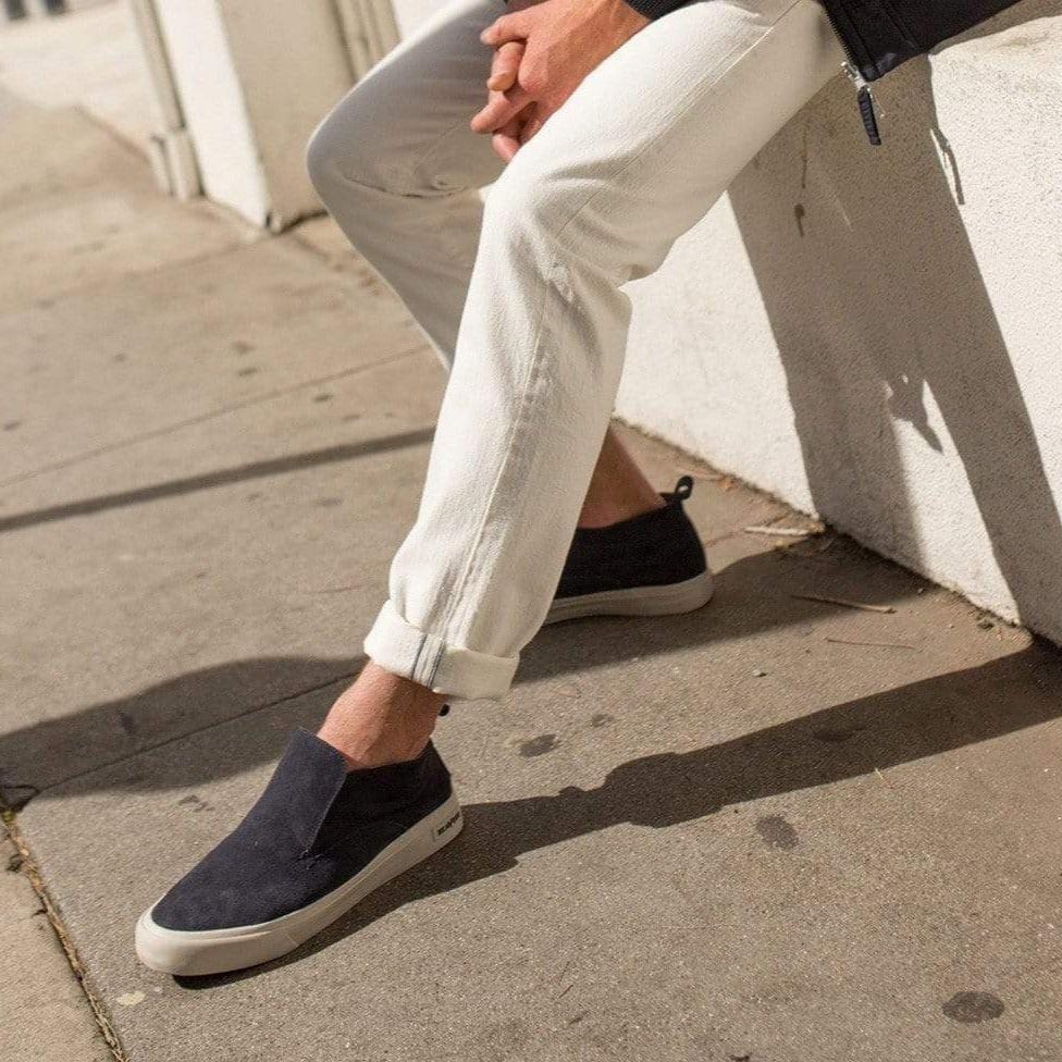 Men's Huntington Middie sneaker in Deep Navy suede, worn with white jogger pants on a sidewalk