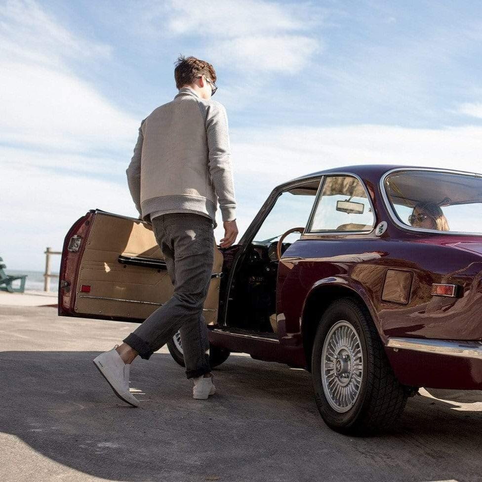 Men's Huntington Middie sneaker in Oyster suede, worn with khaki pants by a person stepping out of a vintage car
