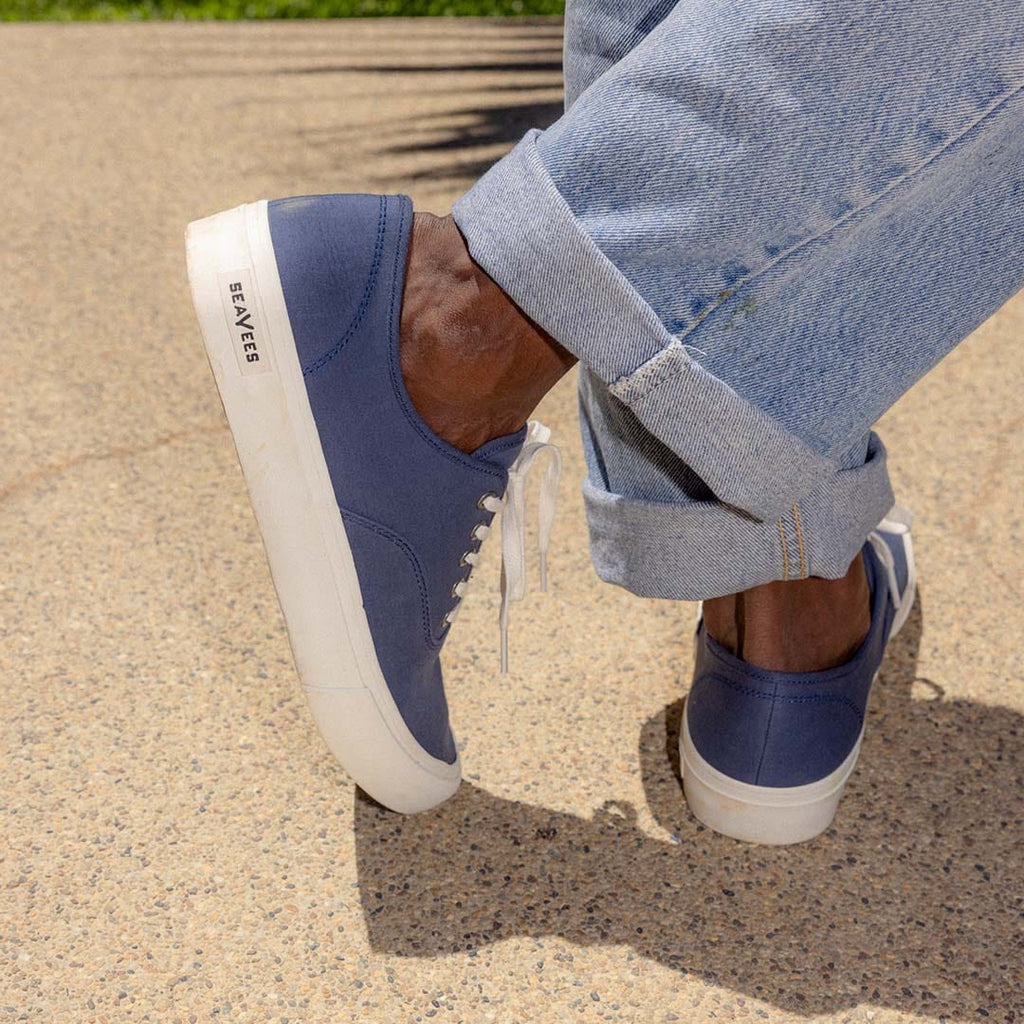 Men's Legend Sneaker in True Navy canvas, close-up worn with cuffed jeans, sole edge visible