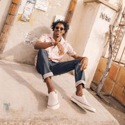 Men's Hawthorne Slip On in Ecru suede, worn with cuffed jeans by a person seated on steps
