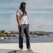 Men's Hermosa Sneaker in Natural canvas, worn with dark pants by a person standing near a harbor