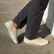 Men's Hermosa Sneaker in Natural canvas, close-up worn with dark pants on a sunny sidewalk