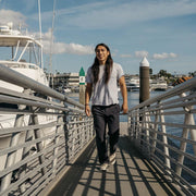 Men's Hermosa Sneaker in Natural canvas, worn with dark pants by a person walking down a marina ramp