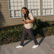 Men's Sixty Six Sneaker in White canvas, worn with dark pants and white socks, walking on a sidewalk