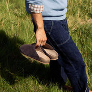 Men's Tiburon Trekker sandal in Espresso suede, held in one hand by a person standing in grass