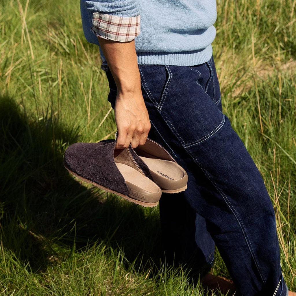 Men's Tiburon Trekker sandal in Espresso suede, held in one hand by a person standing in grass
