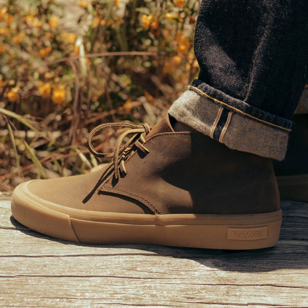 Men's Maslon Desert Boot in Kona leather, side close-up with laces on a wooden deck
