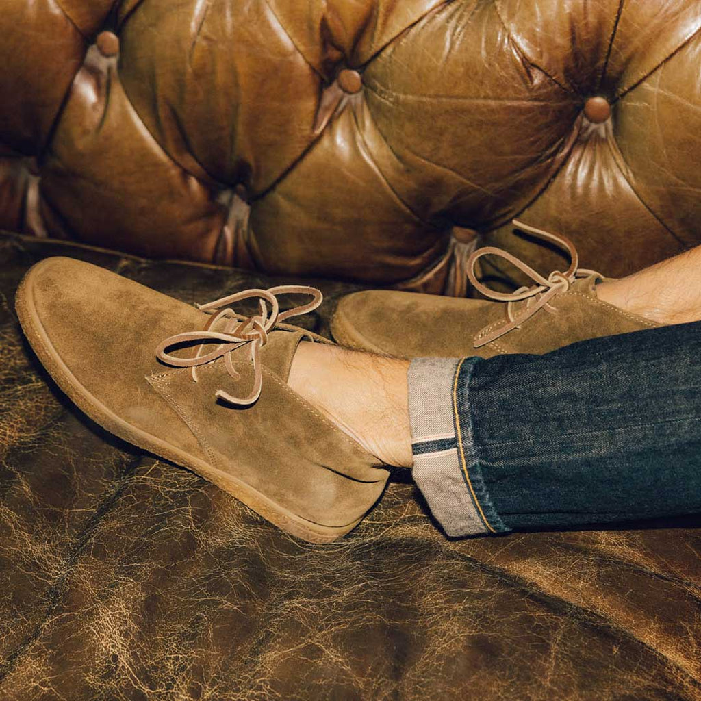 Men's Sun-tans Chukka in Desert Palm suede, close-up worn on a tufted leather sofa