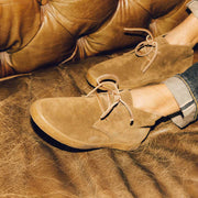 Men's Sun-tans Chukka in Desert Palm suede, close-up of the suede upper and laces, worn on a leather sofa
