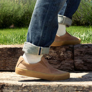 Men's Hawthorne Slip On in Sandstorm leather, worn with rolled jeans on a wooden beam