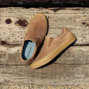 Men's Hawthorne Slip On in Sandstorm leather, pair resting on a weathered wooden beam
