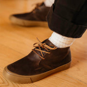 Men's Maslon Desert Boot in Kona leather, close-up of laces, worn with white socks on a wood floor