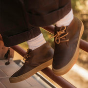 Men's Maslon Desert Boot in Kona leather, close-up worn with white socks and cuffed pants on a railing