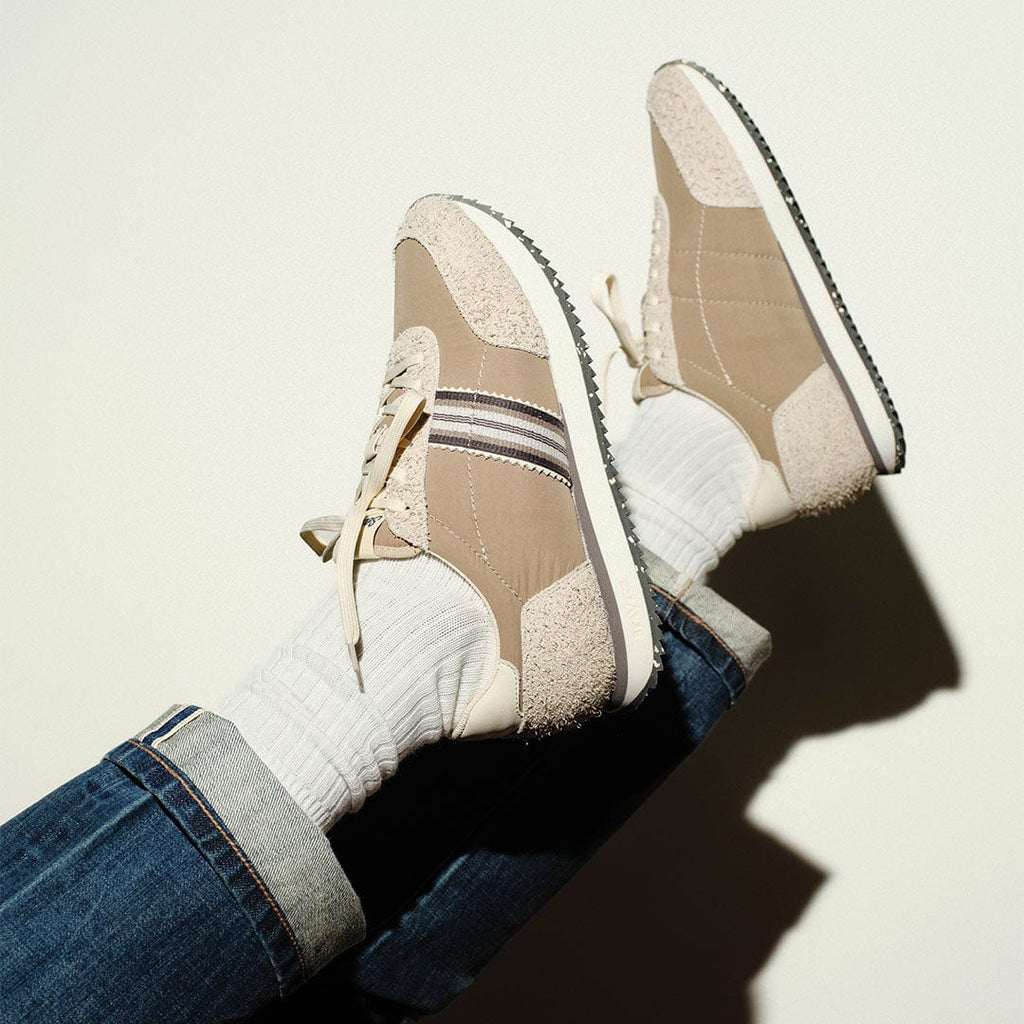 Men's Royal Runner sneaker in Latte nylon and suede, worn with white socks and jeans, feet raised, close up