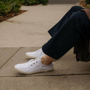 Men's Sixty Six Sneaker in White canvas, worn with dark pants by a person seated on a curb