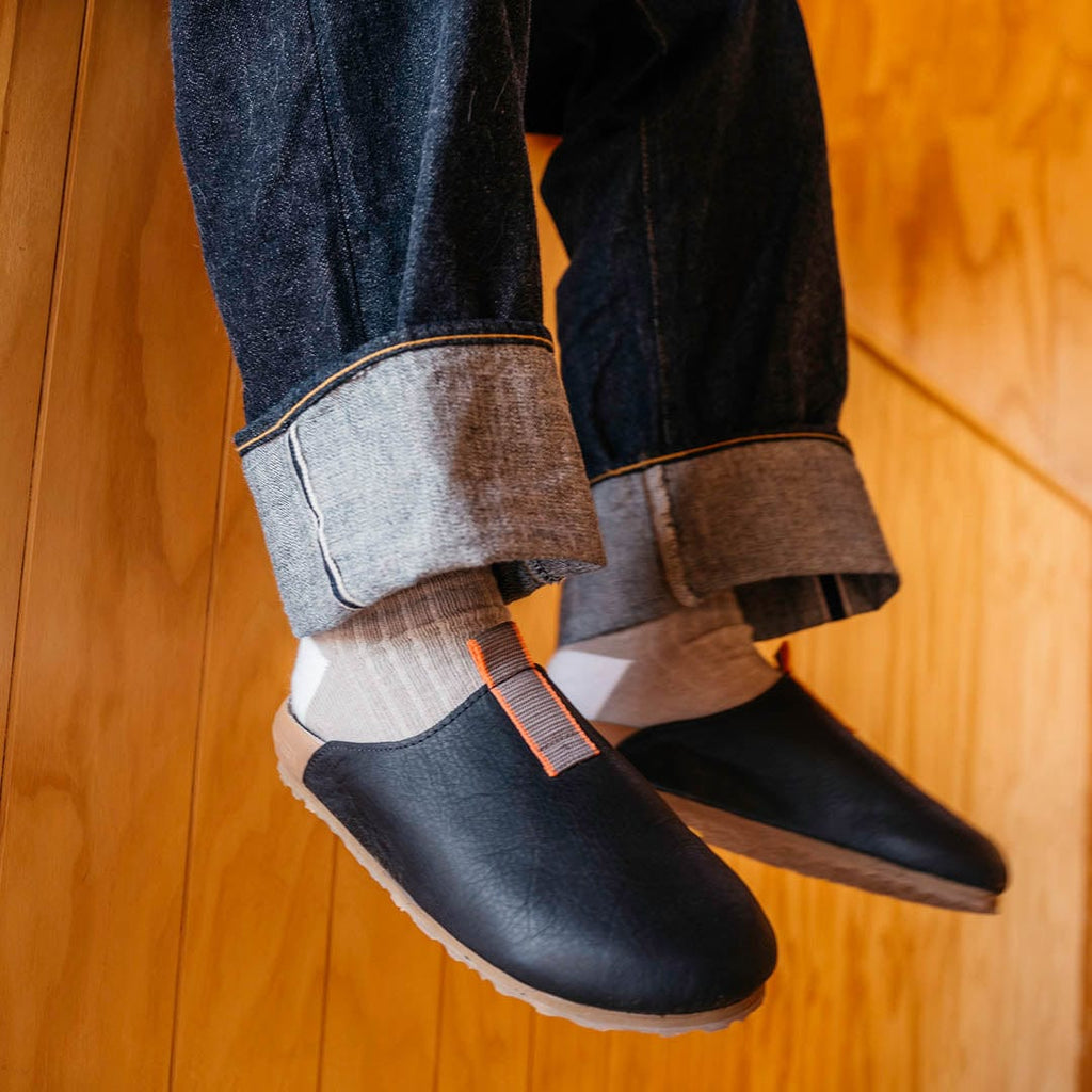 Men's Tiburon Trekker sandal in Black leather, worn with rolled jeans, hanging from a seat, close up