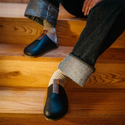 Men's Tiburon Trekker sandal in Black leather, worn with rolled jeans on wooden stairs