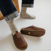 Men's Tiburon Trekker sandal in Elmwood leather, worn with rolled jeans, one shoe showing the outsole