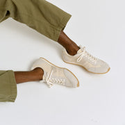 Men's Wilcox Low Profile Trainer sneaker in Cloud nylon and suede, worn with olive pants, seated, side view