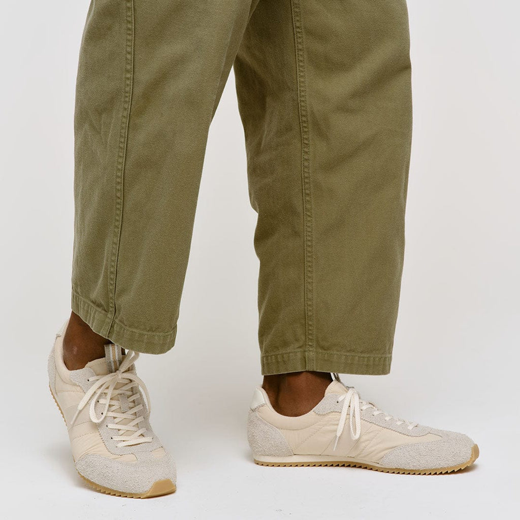 Men's Wilcox Low Profile Trainer sneaker in Cloud nylon and suede, worn with olive pants, standing on a white background