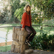 Women's Monterey Sneaker in Black canvas, worn with black pants by a person leaning on a stone pillar