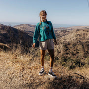 Women's Monterey Sneaker in Black canvas, worn with shorts by a person standing on a hillside trail
