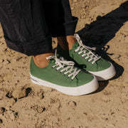 Women's Monterey Sneaker in Cactus canvas, close-up of both shoes, worn with wide black pants on sand