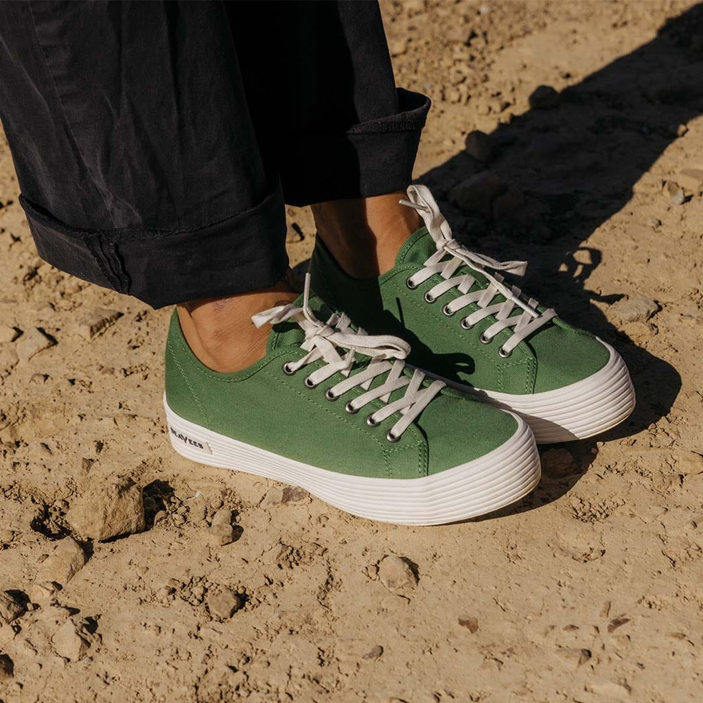 Women's Monterey Sneaker in Cactus canvas, close-up of both shoes, worn with wide black pants on sand
