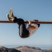 Women's Monterey Sneaker in Cactus canvas, worn by a person hanging from a metal bar above a hillside