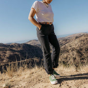 Women's Monterey Sneaker in Cactus canvas, worn with black pants and a white tee on a hilltop trail