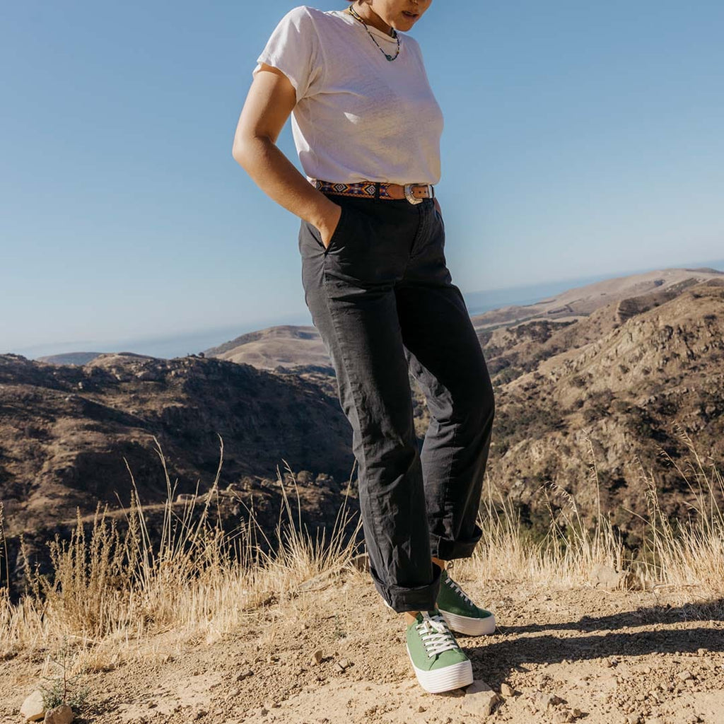 Women's Monterey Sneaker in Cactus canvas, worn with black pants and a white tee on a hilltop trail