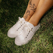Women's Monterey Sneaker in Bleach canvas, close-up with laces, worn on grass