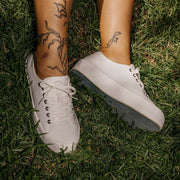 Women's Monterey Sneaker in Bleach canvas, close-up of both shoes, worn with bare ankles on grass