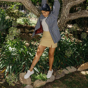 Women's Monterey Sneaker in Bleach canvas, worn with a khaki skirt by a person standing among bushes