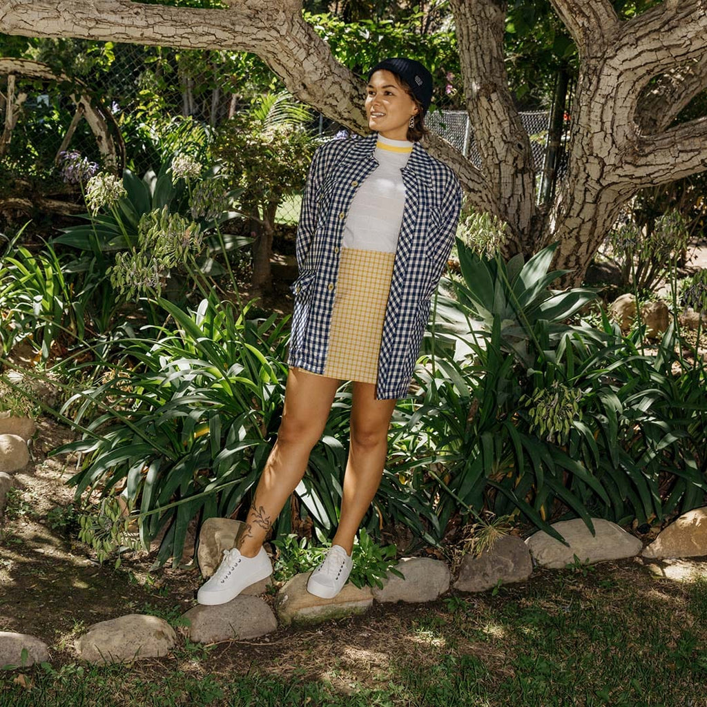 Women's Monterey Sneaker in Bleach canvas, worn with a khaki skirt, full-length view in a garden
