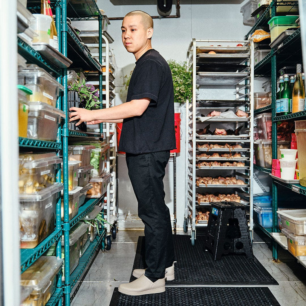 Men's Calistoga Clog in Concrete rubber, worn by a person standing in a commercial kitchen pantry