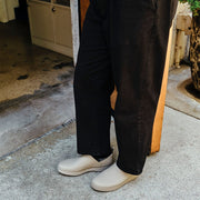 Men's Calistoga Clog in Concrete rubber, worn with black pants on a concrete step