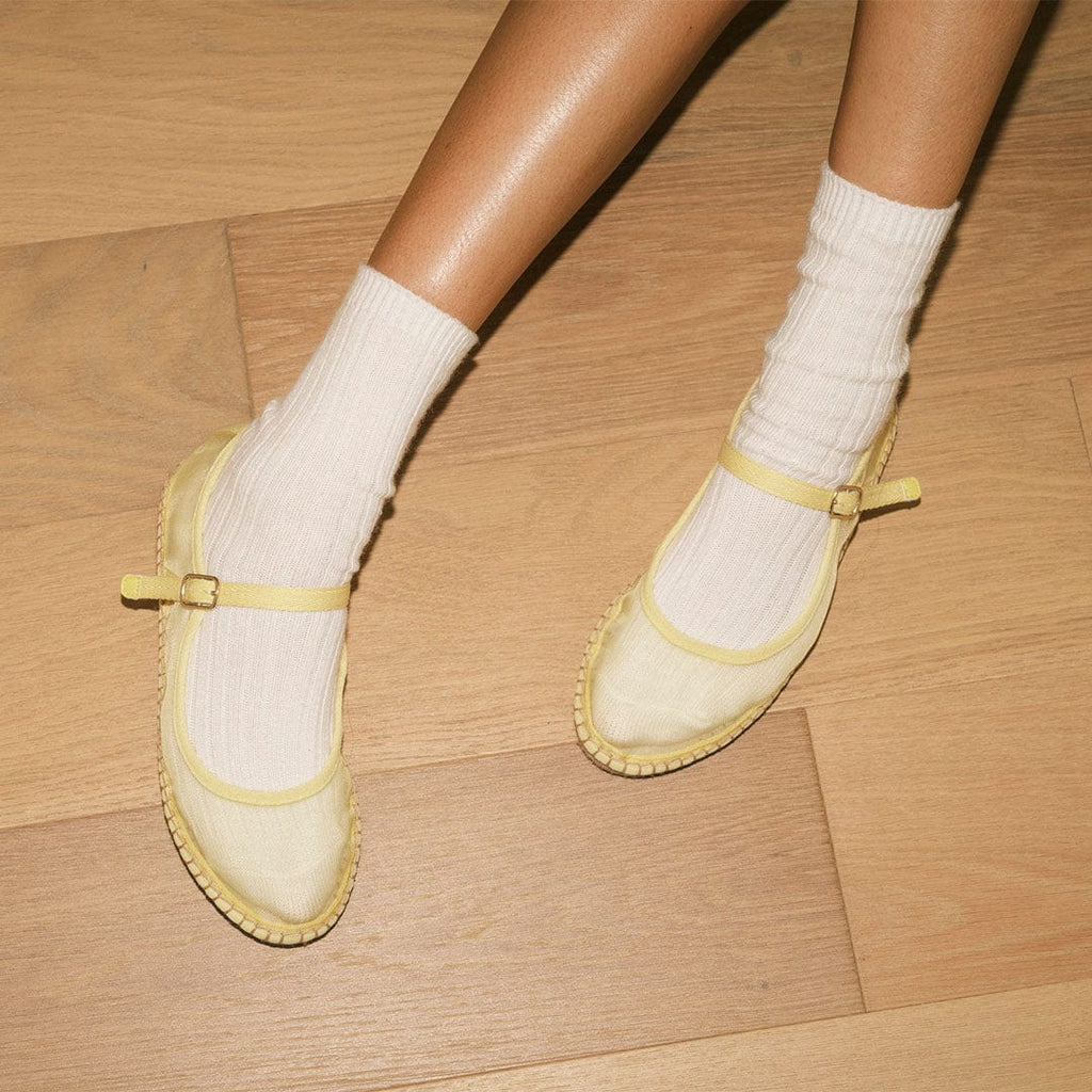 Women's Miramar Espadrille in Butter mesh, worn with white socks on a wood floor, pair from above